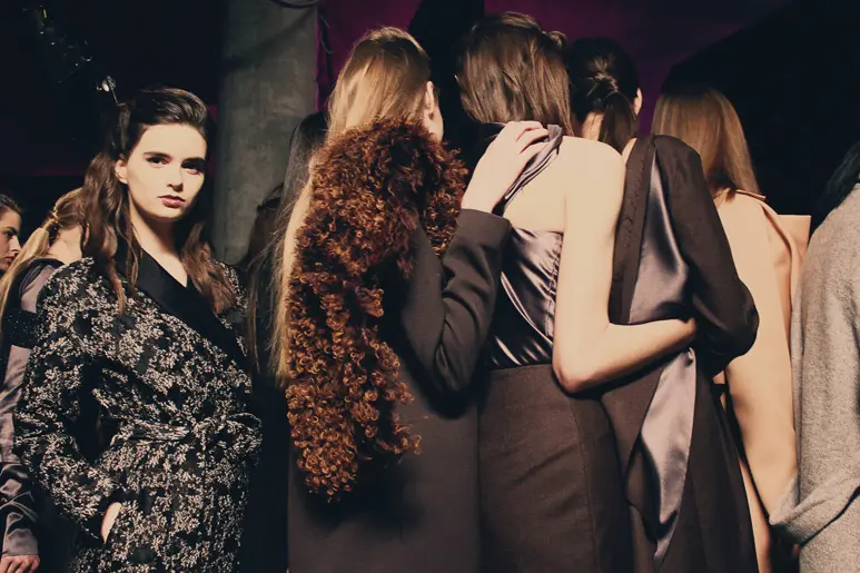 Mannequins en coulisses d’un défilé de mode haute couture, ambiance backstage.
