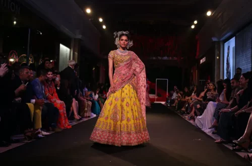 Mannequin portant une robe de mariage indienne jaune et rose lors d’un défilé