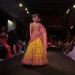 Mannequin portant une robe de mariage indienne jaune et rose lors d’un défilé